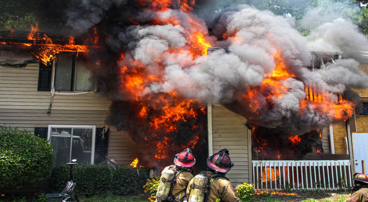 Firefighters outside multistory residential building on fire. 