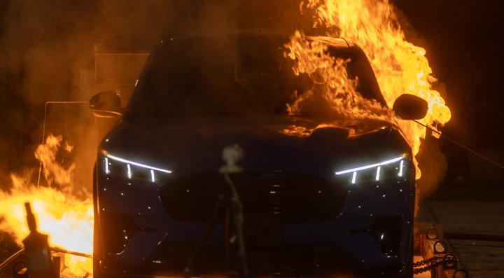 An electric vehicle engulfed in flames during a controlled EV battery fire experiment.