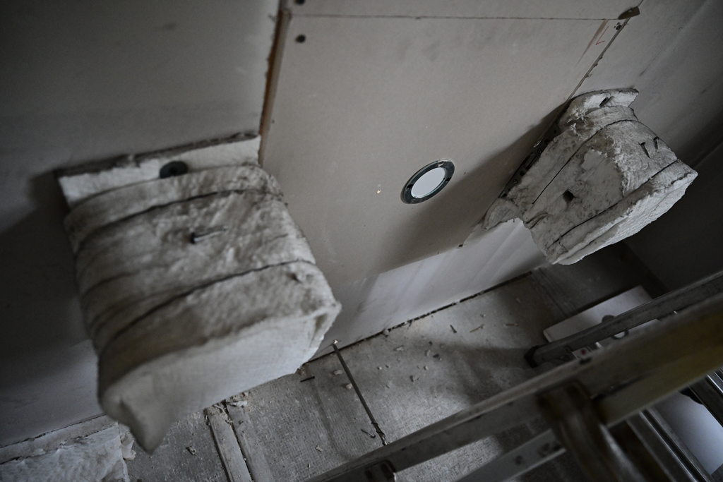 The image shows the lower wall of the compartment in the at-scale experimental setup. On the wall is the filter paper used to measure surface deposition. The ceramic fiber wrapped boxes house the laser and photodiode used to measure obscuration.