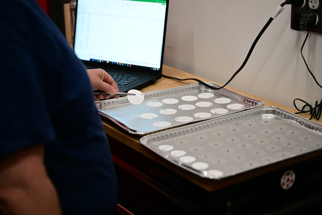The image shows pre-test weighing of the set of gravimetric filters used in a single test. The left tray contains the 15 filters used to measure the gravimetric soot mass. The right tray contains the 35 filters used in cascade impactors to measure the soot size distribution.