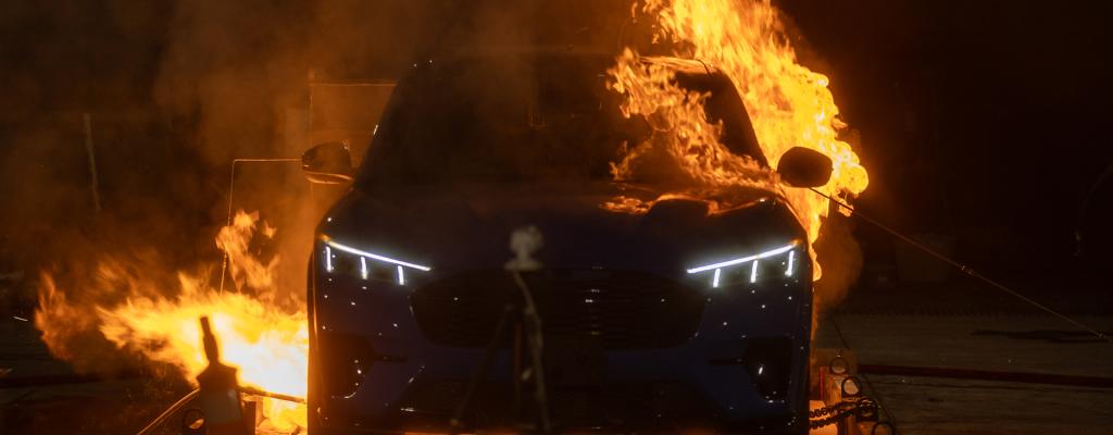 An electric vehicle engulfed in flames during a controlled EV battery fire experiment.