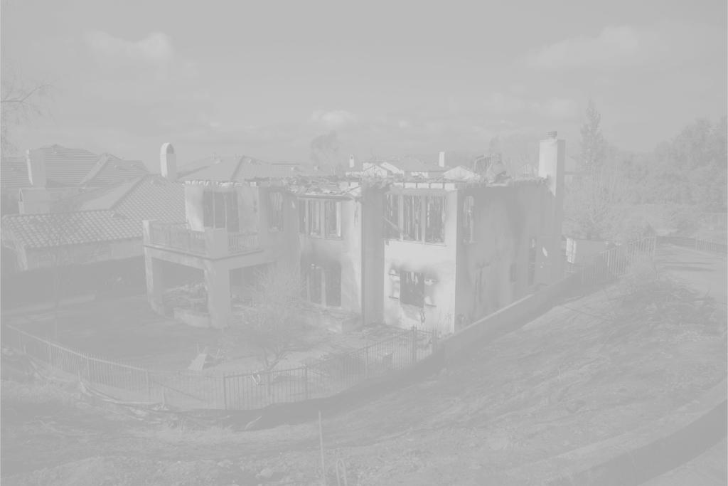 Burnt vegetation and a destroyed home resulting from a WUI fire