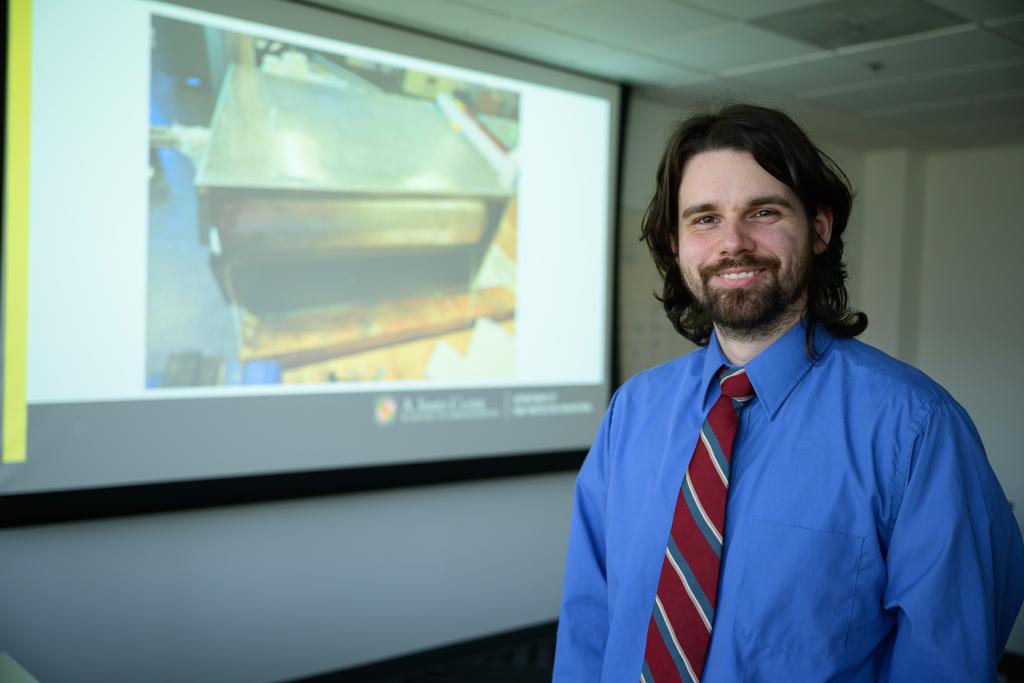 Ian stands in front of his thesis presentation on the use of a phi meter for fire smoke analysis