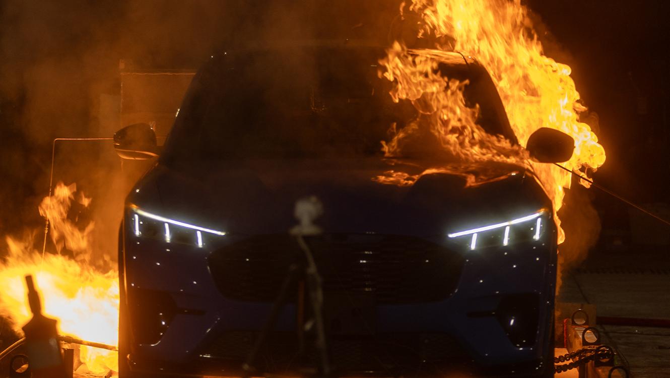 An electric vehicle engulfed in flames during a controlled EV battery fire experiment.