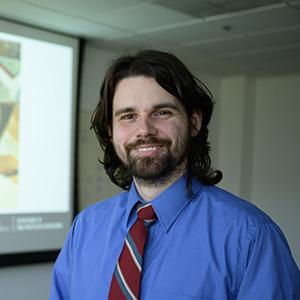Ian stands in front of his thesis presentation