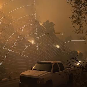 Wildfire spreading across a hillside at night with white contour lines and markers overlaid on top representing wildfire risk modeling